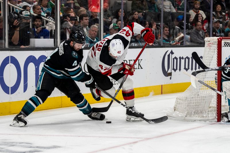 Feb 27, 2024; San Jose, California, USA;  New Jersey Devils center Curtis Lazar (42) is tripped by San Jose Sharks defenseman Kyle Burroughs (4) during the first period behind the net at SAP Center at San Jose. Mandatory Credit: Neville E. Guard-USA TODAY Sports