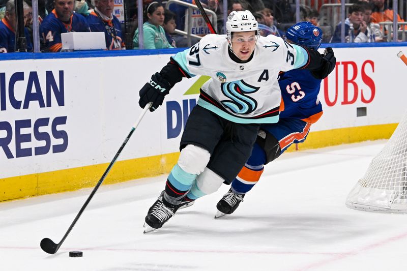 Feb 13, 2024; Elmont, New York, USA; Seattle Kraken center Yanni Gourde (37) skates with the puck from behind the net chased by New York Islanders center Casey Cizikas (53) during the first period at UBS Arena. Mandatory Credit: Dennis Schneidler-USA TODAY Sports