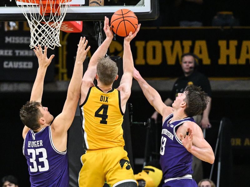 Dec 3, 2024; Iowa City, Iowa, USA; Iowa Hawkeyes guard Josh Dix (4) goes to the basket as Northwestern Wildcats forward Luke Hunger (33) and guard Brooks Barnhizer (13) defend during the first half at Carver-Hawkeye Arena. Mandatory Credit: Jeffrey Becker-Imagn Images