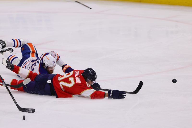 Jun 24, 2024; Sunrise, Florida, USA;Florida Panthers forward Kevin Stenlund (82) and Edmonton Oilers forward Leon Draisaitl (29) reach for the puck during the second period in game seven of the 2024 Stanley Cup Final at Amerant Bank Arena. Mandatory Credit: Sam Navarro-USA TODAY Sports