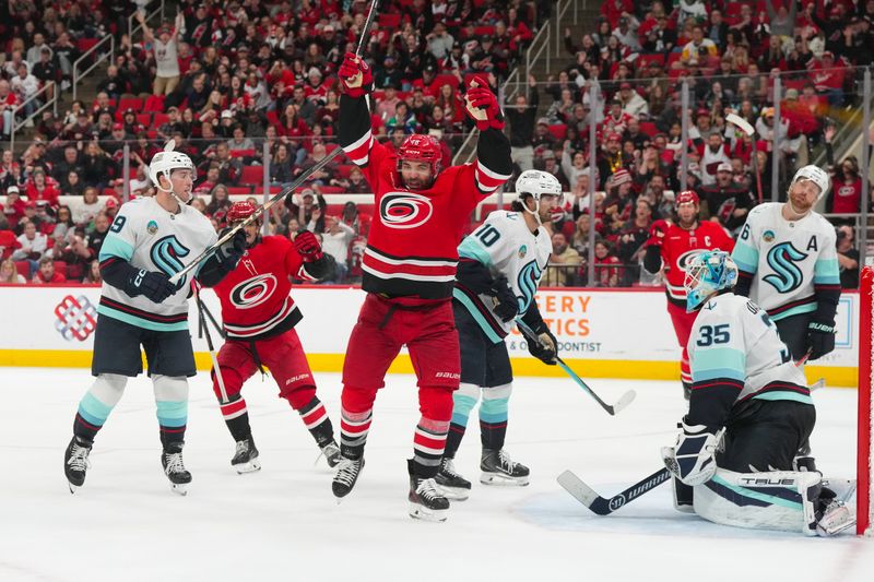 Jan 10, 2026; Raleigh, North Carolina, USA;  Carolina Hurricanes left wing Jordan Martinook (48) watches his goal past Seattle Kraken goaltender Joey Daccord (35) and center Matty Beniers (10) during the third period at Lenovo Center. Mandatory Credit: James Guillory-Imagn Images