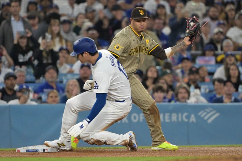 Sep 26, 2024; Los Angeles, California, USA;  Los Angeles Dodgers designated hitter Shohei Ohtani (17) beats the throw to San Diego Padres third baseman Manny Machado (13) in the seventh inning at Dodger Stadium. Mandatory Credit: Jayne Kamin-Oncea-Imagn Images