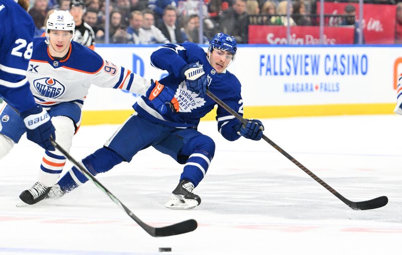 Nov 16, 2024; Toronto, Ontario, CAN;  Toronto Maple Leafs forward Connor Dewar (24) loses his balance as he pursues the puck against the Edmonton Oilers in the first period at Scotiabank Arena. Mandatory Credit: Dan Hamilton-Imagn Images