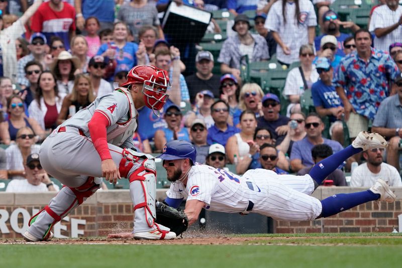 Jul 7, 2024; Chicago, Illinois, USA; Chicago Cubs third baseman Miles Mastrobuoni (20) is safe at home plate as Los Angeles Angels catcher Logan O'Hoppe (14) makes a late tag during the third inning at Wrigley Field. Mandatory Credit: David Banks-USA TODAY Sports