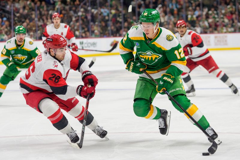 Nov 19, 2025; Saint Paul, Minnesota, USA; Minnesota Wild left wing Matt Boldy (12) looks to shoot and is defended by Carolina Hurricanes defenseman Sean Walker (26) in the second period at Grand Casino Arena. Mandatory Credit: Matt Blewett-Imagn Images