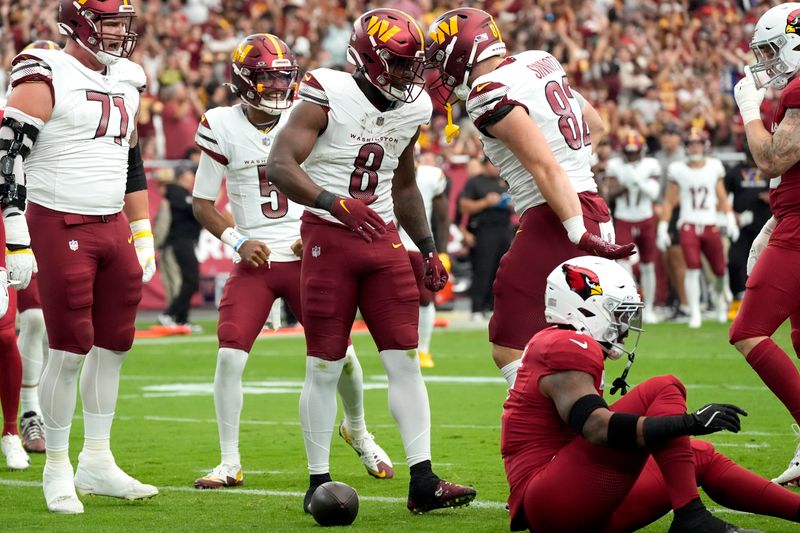 Washington Commanders running back Brian Robinson Jr. (8) celebrates his touchdown with tight end Ben Sinnott (82) during the first half of an NFL football game against the Arizona Cardinals, Sunday, Sept. 29, 2024, in Glendale, Ariz. (AP Photo/Ross D. Franklin)