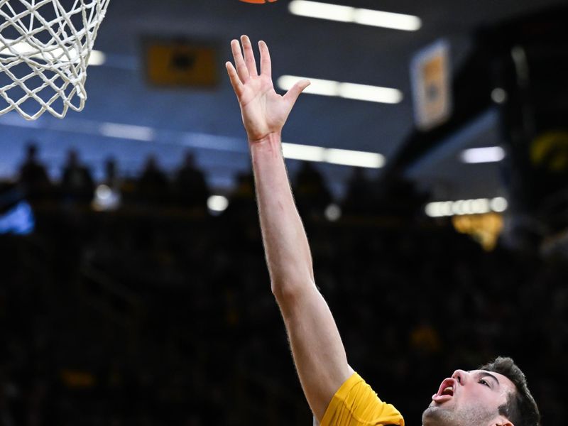 Feb 8, 2026; Iowa City, Iowa, USA; Iowa Hawkeyes forward Alvaro Folgueiras (7) goes to the basket over Northwestern Wildcats guard Jayden Reid (4) during the second half at Carver-Hawkeye Arena. Mandatory Credit: Jeffrey Becker-Imagn Images