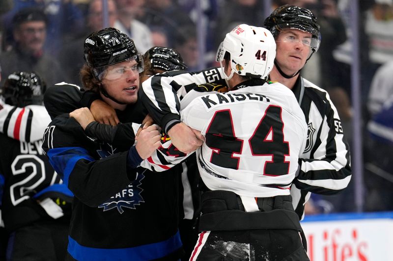 Dec 2, 2024; Toronto, Ontario, CAN; Toronto Maple Leafs forward Nikita Grebenkin (71) and Chicago Blackhawks defenseman Wyatt Kaiser (44) get separated by linesman Kyle Flemington (55) at the end of the game at Scotiabank Arena. Mandatory Credit: John E. Sokolowski-Imagn Images