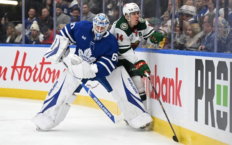 Jan 29, 2025; Toronto, Ontario, CAN;  Minnesota Wild forward Joel Eriksson Ek (14) collides with Toronto Maple Leafs goalie Joseph Woll (60) as they pursue a loose puck in the second period at Scotiabank Arena. Mandatory Credit: Dan Hamilton-Imagn Images