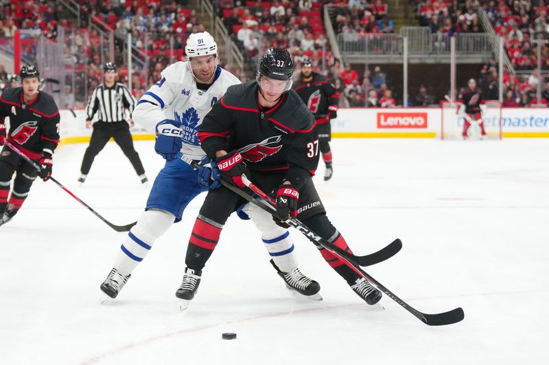 Dec 4, 2025; Raleigh, North Carolina, USA; Carolina Hurricanes right wing Andrei Svechnikov (37) tries to control the puck against Toronto Maple Leafs center John Tavares (91) during the first period at Lenovo Center. Mandatory Credit: James Guillory-Imagn Images