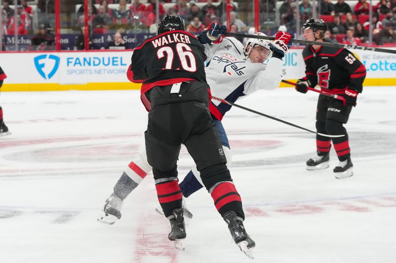 Nov 11, 2025; Raleigh, North Carolina, USA;  Carolina Hurricanes defenseman Sean Walker (26) checks Washington Capitals center Aliaksei Protas (21) during the first period at Lenovo Center. Mandatory Credit: James Guillory-Imagn Images