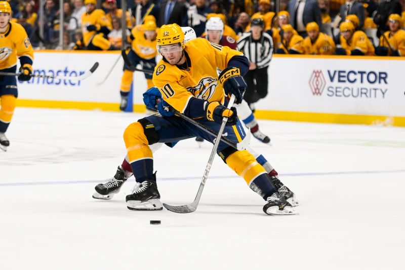  Nov 2, 2024; Nashville, Tennessee, USA;  Nashville Predators center Colton Sissons (10) skates with the puck as Colorado Avalanche defenseman Oliver Kylington (58) pokes it awayduring the first period at Bridgestone Arena. Mandatory Credit: Steve Roberts-Imagn Images