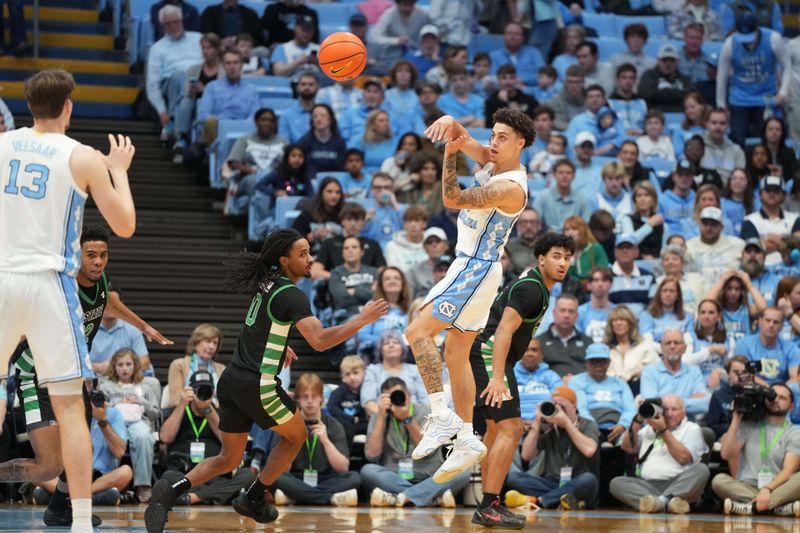 Dec 13, 2025; Chapel Hill, North Carolina, USA; North Carolina Tar Heels guard Kyan Evans (0) passes the ball to center Henri Veesaar (13) as USC Upstate Spartans guard Tyler Smith (0) defends at Dean E. Smith Center. Mandatory Credit: Bob Donnan-Imagn Images