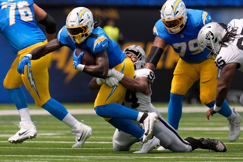 Los Angeles Chargers running back Gus Edwards (4) runs against Las Vegas Raiders defensive tackle Christian Wilkins during the first half of an NFL football game, Sunday, Sept. 8, 2024, in Inglewood, Calif. (AP Photo/Marcio Jose Sanchez)