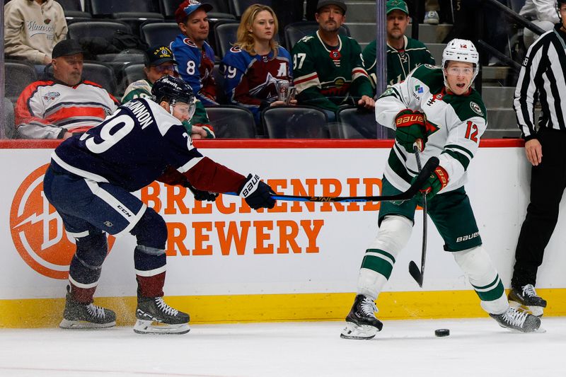 Feb 26, 2026; Denver, Colorado, USA; Minnesota Wild left wing Matt Boldy (12) scores his second open net goal as Colorado Avalanche center Nathan MacKinnon (29) defends in the third period at Ball Arena. Mandatory Credit: Isaiah J. Downing-Imagn Images