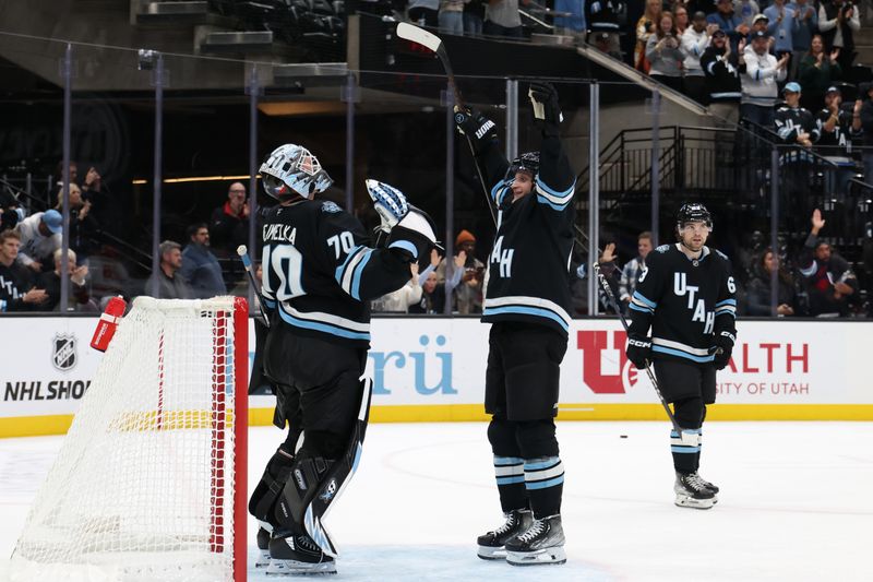 Nov 13, 2024; Salt Lake City, Utah, USA; Utah Hockey Club goaltender Karel Vejmelka (70) celebrates a win over the Carolina Hurricanes with defenseman Shayne Gostisbehere (4)  at Delta Center. Mandatory Credit: Rob Gray-Imagn Images