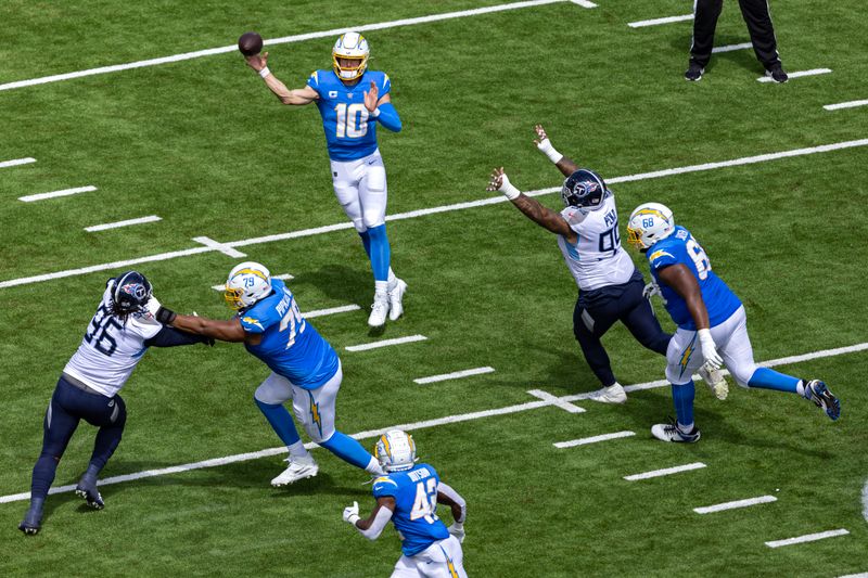 Los Angeles Chargers quarterback Justin Herbert (10) throws running back Elijah Dotson (42) as he's pressured by Tennessee Titans linebacker Rashad Weaver (99) during their NFL football game Sunday, Sept. 17, 2023, in Nashville, Tenn. (AP Photo/Wade Payne)