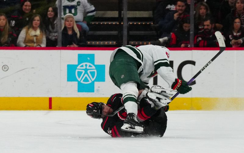 Jan 21, 2024; Raleigh, North Carolina, USA;  Minnesota Wild right wing Adam Raska (51) and Carolina Hurricanes defenseman Brett Pesce (22) collide during the third period at PNC Arena. Mandatory Credit: James Guillory-USA TODAY Sports