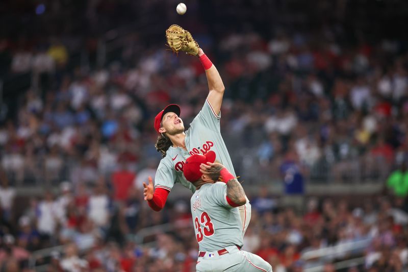 Jul 5, 2024; Atlanta, Georgia, USA; Philadelphia Phillies first baseman Alec Bohm (28) catches a pop fly over third baseman Edmundo Sosa (33) against the Atlanta Braves in the ninth inning at Truist Park. Mandatory Credit: Brett Davis-USA TODAY Sports