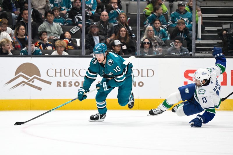 Nov 28, 2025; San Jose, California, USA; San Jose Sharks center Ty Dellandrea (10) controls the puck against Vancouver Canucks left winger Arshdeep Bains (13) in the first period at SAP Center at San Jose. Mandatory Credit: Eakin Howard-Imagn Images