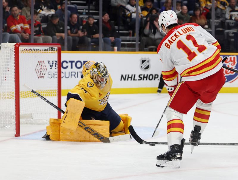 Nov 1, 2025; Nashville, Tennessee, USA; Calgary Flames center Mikael Backlund (11) attacks the goal tended by Nashville Predators goalie Juuse Saros (74) during the second period at Bridgestone Arena. Mandatory Credit: Alan Poizner-Imagn Images