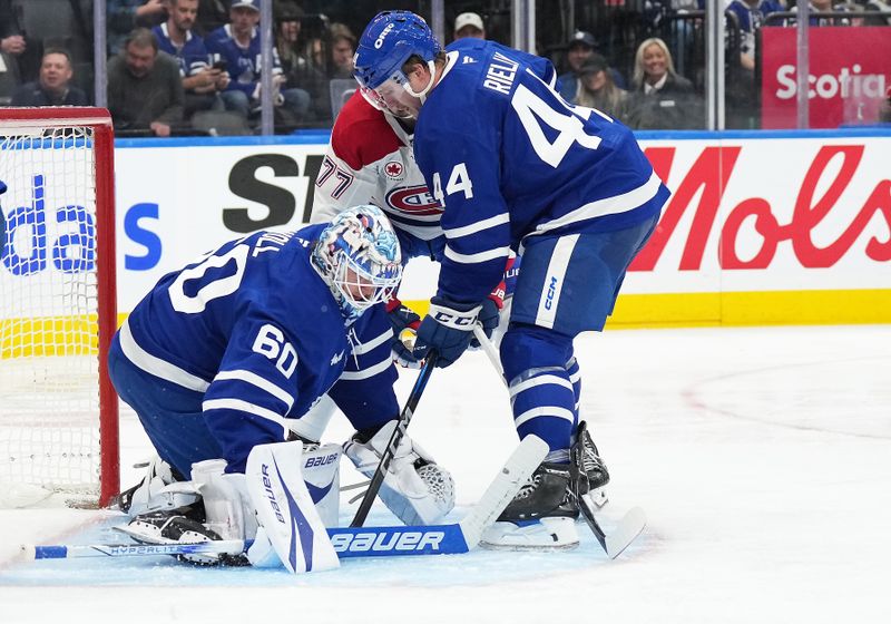 Nov 9, 2024; Toronto, Ontario, CAN; Montreal Canadiens center Kirby Dach (77) battles for the puck with Toronto Maple Leafs defenseman Morgan Rielly (44) in front of goaltender Joseph Woll (60) during the second period at Scotiabank Arena. Mandatory Credit: Nick Turchiaro-Imagn Images