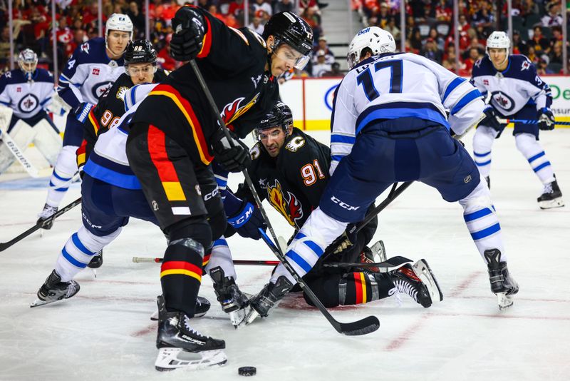 Oct 26, 2024; Calgary, Alberta, CAN; Calgary Flames center Nazem Kadri (91) and Winnipeg Jets center Adam Lowry (17) face off for the puck during the second period at Scotiabank Saddledome. Mandatory Credit: Sergei Belski-Imagn Images