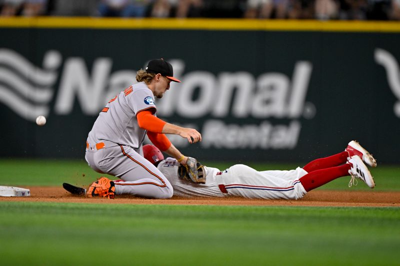 Jun 30, 2025; Arlington, Texas, USA; Texas Rangers center fielder Michael Helman (24) slides into second base as the ball gets past Baltimore Orioles shortstop Gunnar Henderson (2) during the seventh inning at Globe Life Field. Mandatory Credit: Jerome Miron-Imagn Images