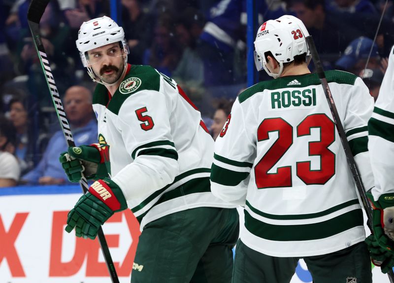 Jan 18, 2024; Tampa, Florida, USA; Minnesota Wild defenseman Jake Middleton (5) is congratulated after scoring against the Tampa Bay Lightning during the second period at Amalie Arena. Mandatory Credit: Kim Klement Neitzel-USA TODAY Sports