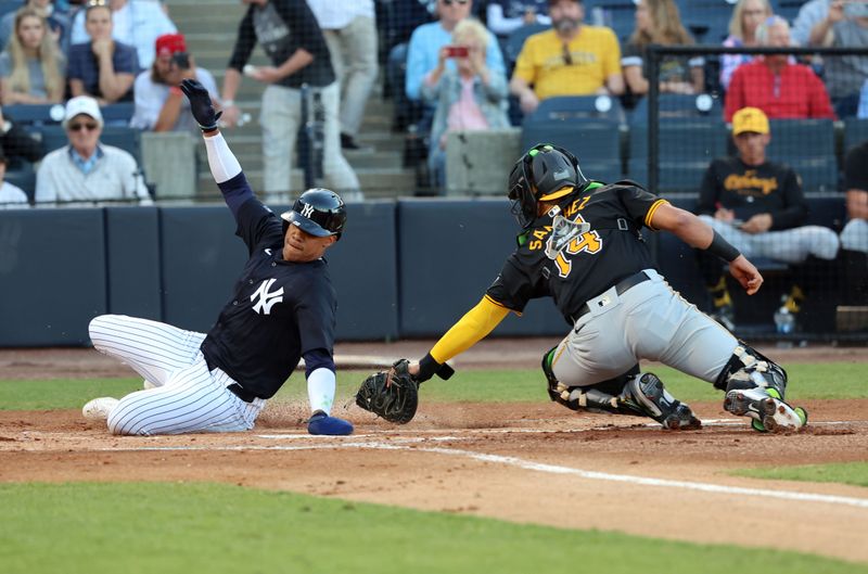 Mar 20, 2024; Tampa, Florida, USA; New York Yankees left fielder Juan Soto (22) slides safe at home plate as Pittsburgh Pirates catcher Ali Sanchez (14) attempts to tag him out as he scores a run during the first inning at George M. Steinbrenner Field. Mandatory Credit: Kim Klement Neitzel-USA TODAY Sports