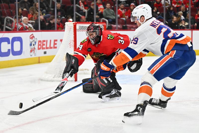 Jan 19, 2024; Chicago, Illinois, USA; Chicago Blackhawks goaltender Petr Mrazek (34) swats the puck away from New York Islanders forward Brock Nelson (29) in the second period at United Center. Mandatory Credit: Jamie Sabau-USA TODAY Sports