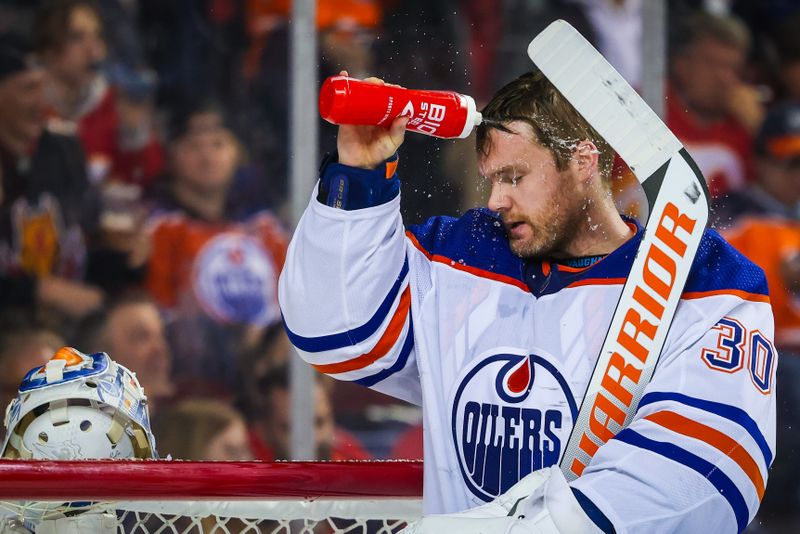 Apr 6, 2024; Calgary, Alberta, CAN; Edmonton Oilers goaltender Calvin Pickard (30) sprays water in his face during the second period against the Calgary Flames at Scotiabank Saddledome. Mandatory Credit: Sergei Belski-USA TODAY Sports