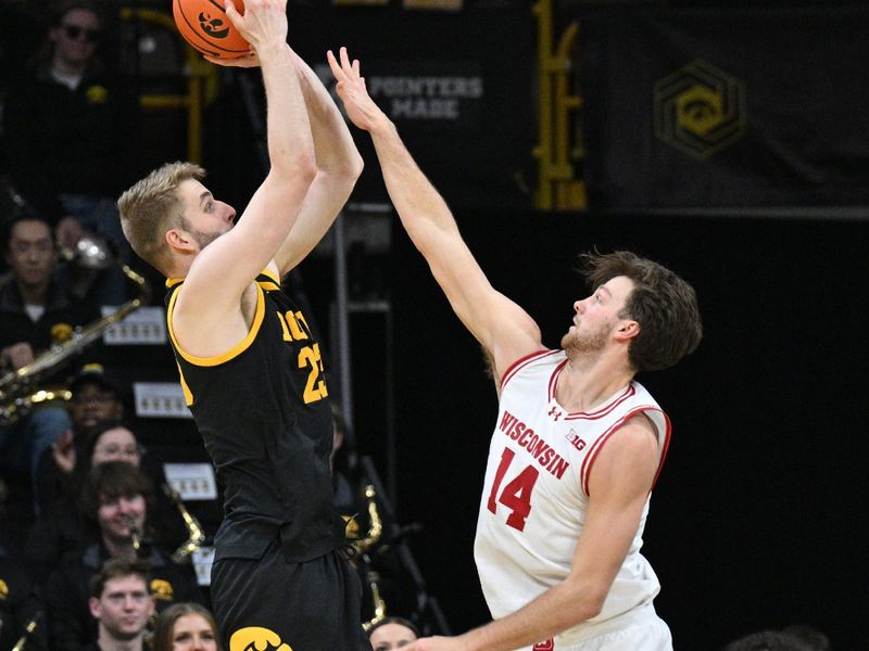 Feb 17, 2024; Iowa City, Iowa, USA; Wisconsin Badgers forward Carter Gilmore (14) defends the shot of Iowa Hawkeyes forward Ben Krikke (23) during the first half at Carver-Hawkeye Arena. Mandatory Credit: Jeffrey Becker-USA TODAY Sports