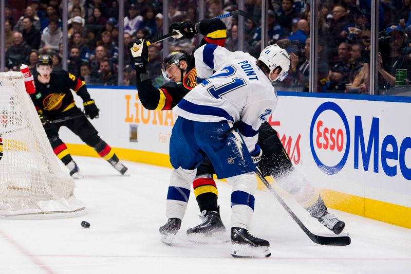 Dec 12, 2023; Vancouver, British Columbia, CAN; Tampa Bay Lightning forward Brayden Point (21) battles with Vancouver Canucks defenseman Nikita Zadorov (91) in the first period at Rogers Arena. Mandatory Credit: Bob Frid-USA TODAY Sports