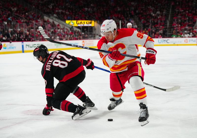 Mar 10, 2024; Raleigh, North Carolina, USA;  Calgary Flames left wing Andrei Kuzmenko (96) cuts with the puck inside Carolina Hurricanes center Jesperi Kotkaniemi (82) during the second period at PNC Arena. Mandatory Credit: James Guillory-USA TODAY Sports