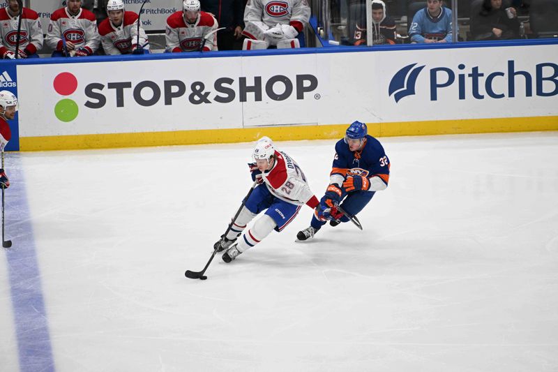 Apr 11, 2024; Elmont, New York, USA; Montreal Canadiens center Christian Dvorak (28) skates with the puck chased by New York Islanders center Kyle MacLean (32) during the second period at UBS Arena. Mandatory Credit: Dennis Schneidler-USA TODAY Sports