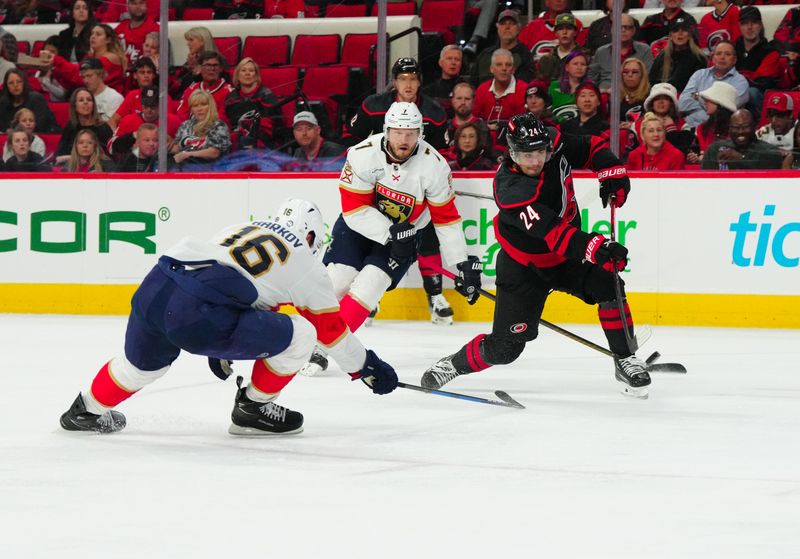 Mar 14, 2024; Raleigh, North Carolina, USA; Carolina Hurricanes center Seth Jarvis (24) gets the shot away against Florida Panthers center Aleksander Barkov (16) during the first period at PNC Arena. Mandatory Credit: James Guillory-USA TODAY Sports