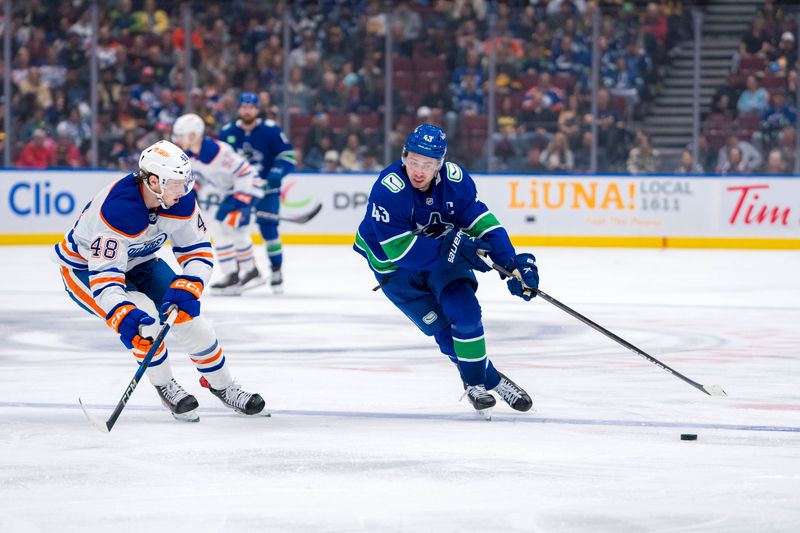 Oct 4, 2024; Vancouver, British Columbia, CAN; Vancouver Canucks defenseman Quinn Hughes (43) drives past Edmonton Oilers forward Noah Philp (48) during the third period at Rogers Arena. Mandatory Credit: Bob Frid-Imagn Images