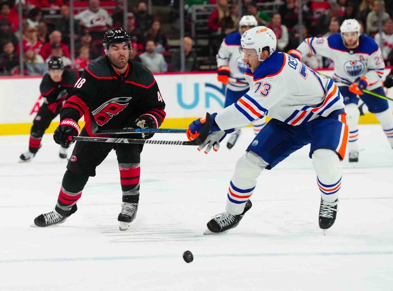 Nov 22, 2023; Raleigh, North Carolina, USA; Carolina Hurricanes left wing Jordan Martinook (48) and Edmonton Oilers defenseman Vincent Desharnais (73) chase after the puck during the third period at PNC Arena. Mandatory Credit: James Guillory-USA TODAY Sports