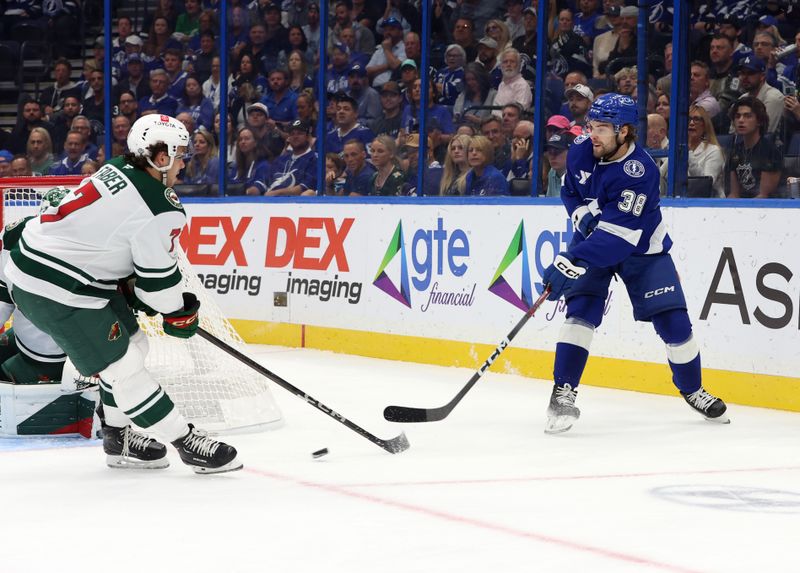 Oct 24, 2024; Tampa, Florida, USA; Tampa Bay Lightning left wing Brandon Hagel (38) passes the puck as Minnesota Wild defenseman Brock Faber (7) defends during the first period at Amalie Arena. Mandatory Credit: Kim Klement Neitzel-Imagn Images