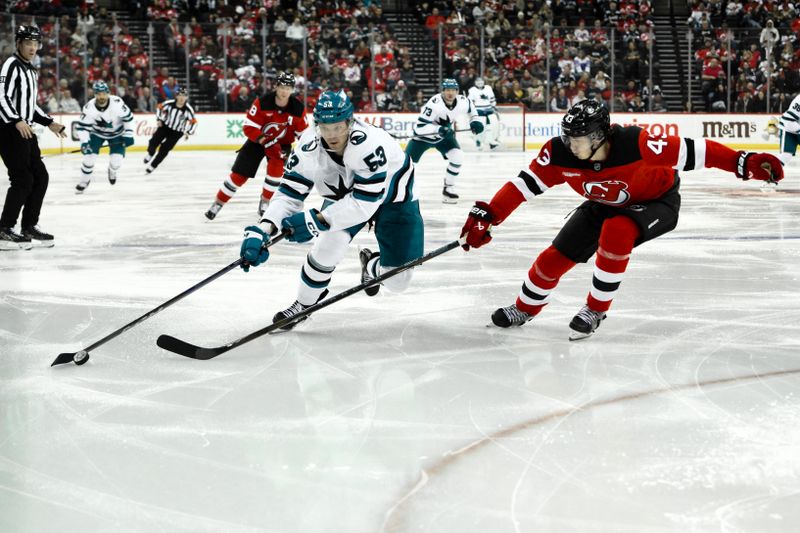 Nov 10, 2024; Newark, New Jersey, USA; San Jose Sharks center Ty Dellandrea (53) skates with the puck against New Jersey Devils defenseman Luke Hughes (43) during the third period at Prudential Center. Mandatory Credit: John Jones-Imagn Images