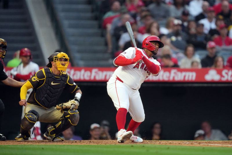 Jun 3, 2024; Anaheim, California, USA; Los Angeles Angels designated hitter Willie Calhoun (5) hits a RBI single in the fourth inning as San Diego Padres catcher Kyle Higashioka (20) watches at Angel Stadium. Mandatory Credit: Kirby Lee-USA TODAY Sports