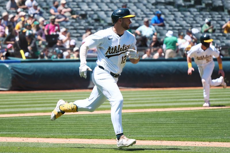 May 23, 2024; Oakland, California, USA; Oakland Athletics shortstop Max Shuemann (12) bats in catcher Kyle McCann (52) on an RBI single against the Colorado Rockies during the seventh inning at Oakland-Alameda County Coliseum. Mandatory Credit: Kelley L Cox-USA TODAY Sports