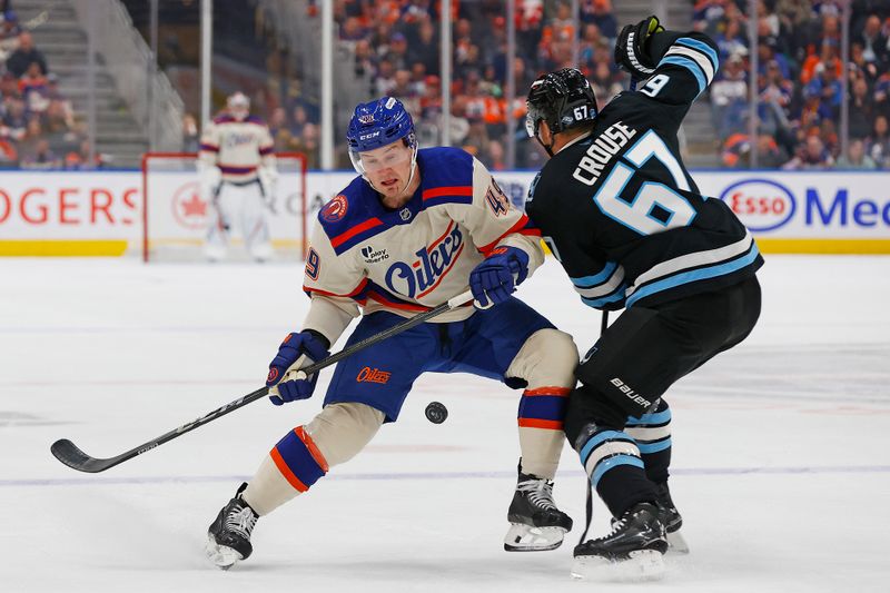 Oct 28, 2025; Edmonton, Alberta, CAN; Edmonton Oilers defensemen Ty Emberson (49) and Utah Mammoth forward Lawson Crouse (67) battle for a loose puck during the first period at Rogers Place. Mandatory Credit: Perry Nelson-Imagn Images