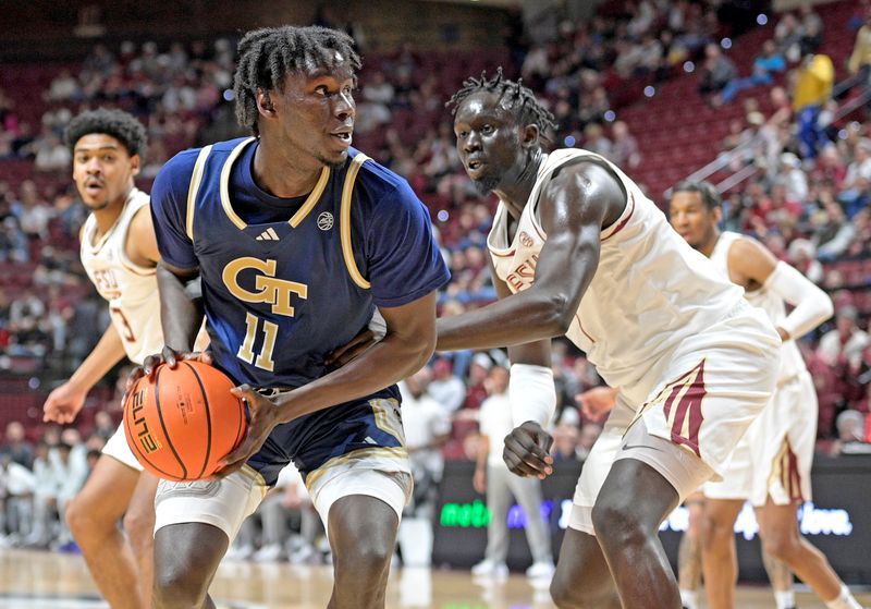 Jan 18, 2025; Tallahassee, Florida, USA; Georgia Tech Yellowjackets forward Baye Ndongo (11) handles the ball against Florida State Seminoles forward Jerry Deng (7) during the first half at Donald L. Tucker Center. Mandatory Credit: Robert Myers-Imagn Images