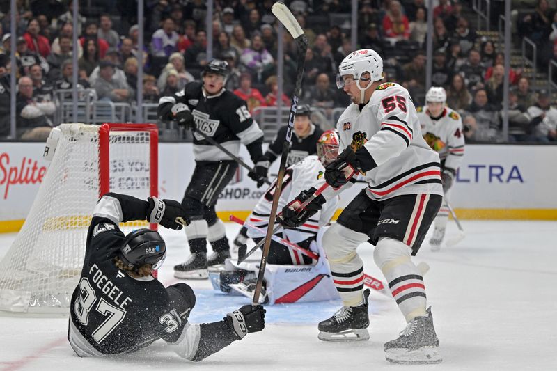 Dec 4, 2025; Los Angeles, California, USA;  Los Angeles Kings left wing Warren Foegele (37) is knocked over as Chicago Blackhawks defenseman Artyom Levshunov (55) defends a shot on goal during the second period at Crypto.com Arena. Mandatory Credit: Jayne Kamin-Oncea-Imagn Images