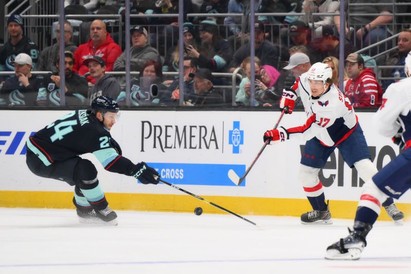 Mar 14, 2024; Seattle, Washington, USA; Washington Capitals center Dylan Strome (17) passes the puck past Seattle Kraken defenseman Jamie Oleksiak (24) during the second period at Climate Pledge Arena. Mandatory Credit: Steven Bisig-USA TODAY Sports