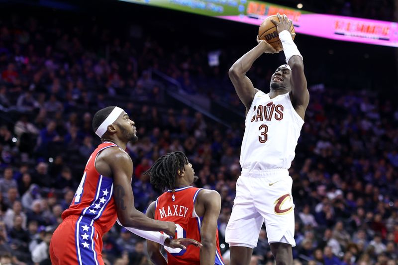 PHILADELPHIA, PENNSYLVANIA - FEBRUARY 23: Caris LeVert #3 of the Cleveland Cavaliers shoots over Paul Reed #44 and Tyrese Maxey #0 of the Philadelphia 76ers during the fourth quarter at the Wells Fargo Center on February 23, 2024 in Philadelphia, Pennsylvania. (Photo by Tim Nwachukwu/Getty Images)