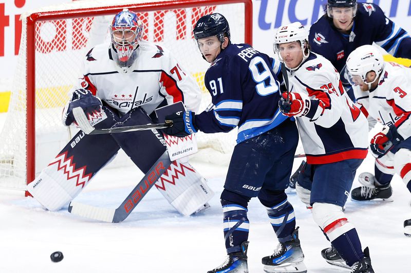 Mar 11, 2024; Winnipeg, Manitoba, CAN; Washington Capitals goaltender Charlie Lindgren (79), Winnipeg Jets center Cole Perfetti (91) and Washington Capitals center Michael Sgarbossa (23) eye an incoming puck in the third period at Canada Life Centre. Mandatory Credit: James Carey Lauder-USA TODAY Sports