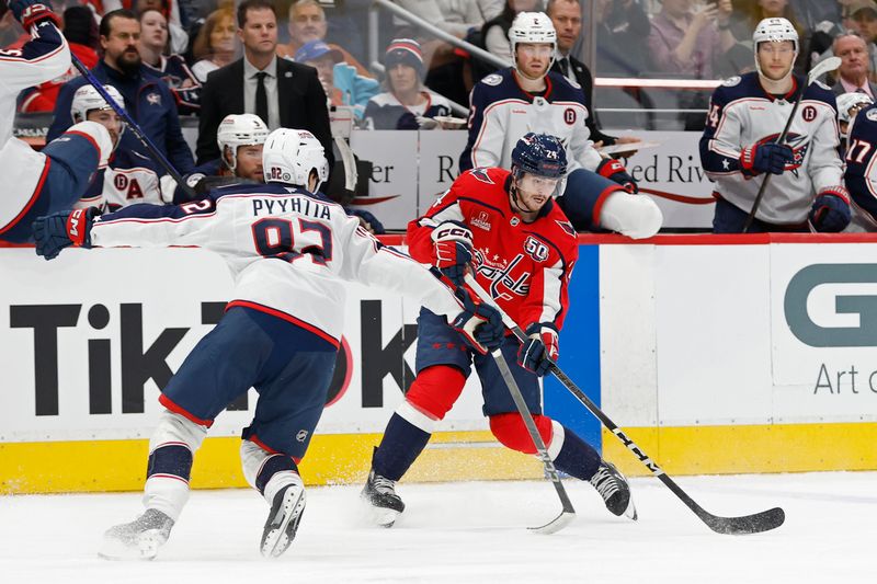 Nov 2, 2024; Washington, District of Columbia, USA; Washington Capitals center Connor McMichael (24) passes the puck as Columbus Blue Jackets left wing Mikael Pyyhtia (82) defends in the third period at Capital One Arena. Mandatory Credit: Geoff Burke-Imagn Images